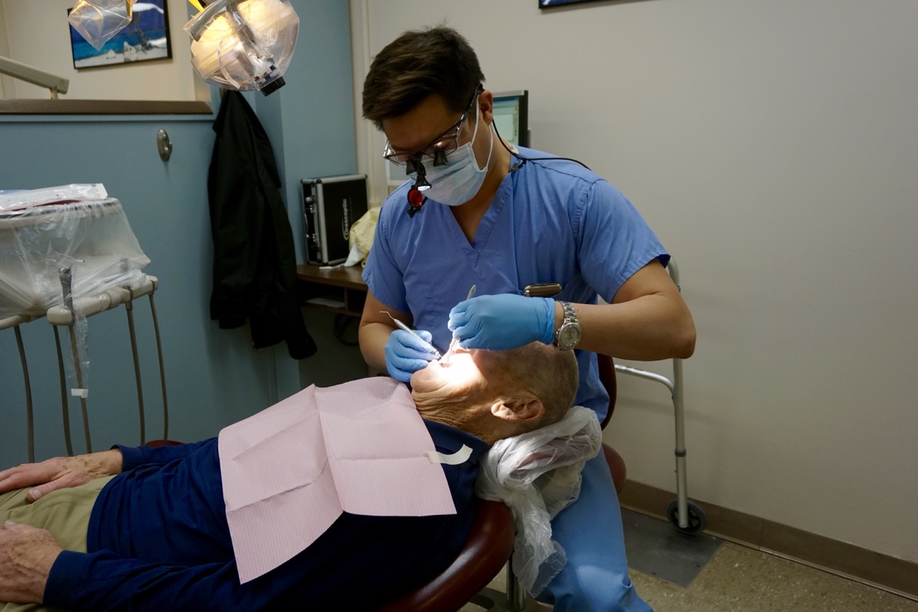 Jeffrey Pan, student commencement speaker for the UConn School of Dental Medicine Class of 2016, with a patient in the dental clinic. (Photo by Ze Horak)